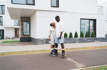 Black couple in roller blades hugging on street