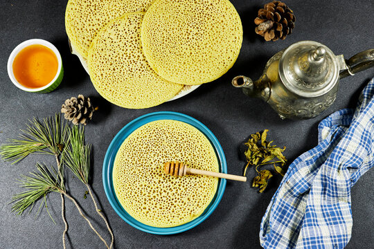 Moroccan or Algerian pancakes named Baghrir in arabic with honey syrup with teapot and dry mint, pine cones