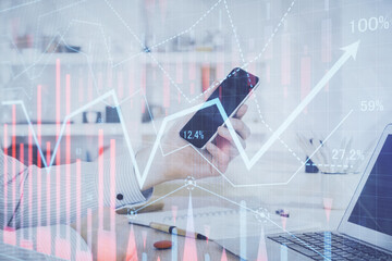 Double exposure of man's hands holding and using a digital device and forex graph drawing. Financial market concept.