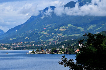 Fototapeta premium Blick auf den Millstätter See mit Millstatt und den wolkenverhangenen Nockbergen in Kärnten