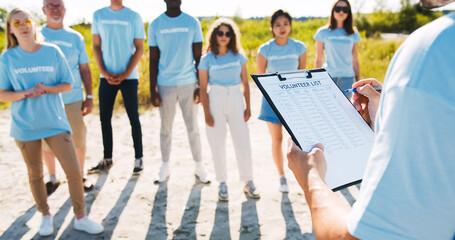 Obraz premium Close up of a clipboard with the volunteer list. The leader dividing responsibilities and checking the presence of members, participants. Nature and environment conservation concept. Save ecology.