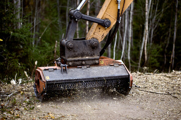 Excavator mulching head is forestry mulcher for clears vegetation of road side.