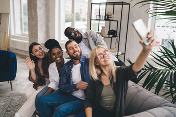 Cheerful smiling diverse colleagues taking selfie in modern office
