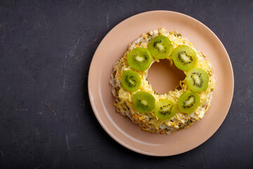 Salad with chicken and kiwi and nuts on a plate on a gray table. copy space.