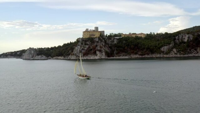 aerial view of sailing ship in the sea in front of duino castle in gulf of trieste