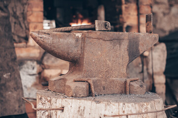 Process metal with hammer on anvil in forge. Strike iron outdoors in workshop with fire. Metalworking, blacksmithing.