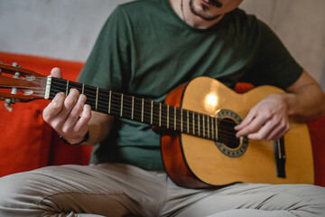 One man adult Caucasian sit at home on sofa bed in room play guitar