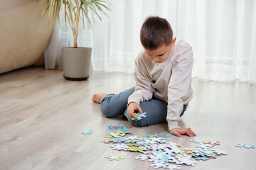 Child boy lies on warm floor and puts puzzles. Educational logic toys for kid's. Games for ?hild development, train mindfulness
