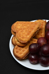 Delicious waffles and grapes on a plate. A sweet breakfast of waffles and red grapes. Heart-shaped waffles.