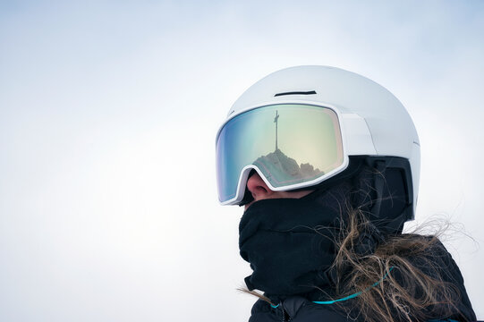 Skifahrerin mit wei&szlig;en Helm und Gipfelkreuz Reflexion in der Brille