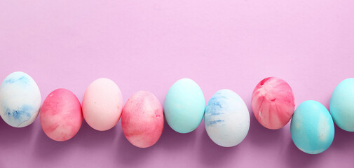Row of painted Easter eggs on lilac background
