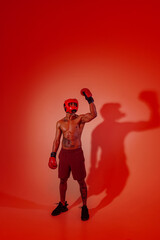 Sporty man wearing head guard and boxing gloves practicing for fight on studio background