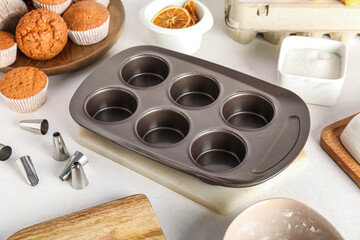 Muffin tray and piping tips on light background