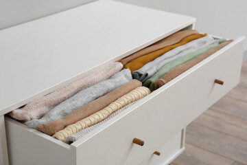 Fototapeta na wymiar Open drawer with folded clothes in room, closeup