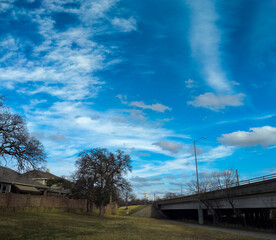 Obraz premium Scattered clouds in a deep blue sky over a suburban neighborhood