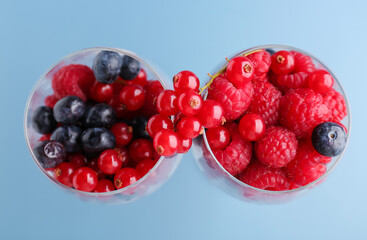 Glasses of fresh berries on color background