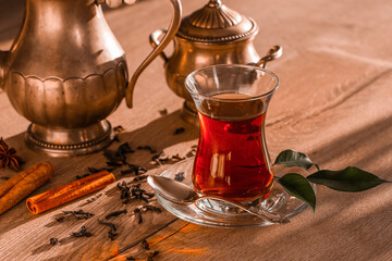 Glass cup of Turkish tea and dry leaves on wooden background