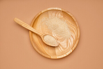 Wooden plate and spoon with amaranth seeds on color background