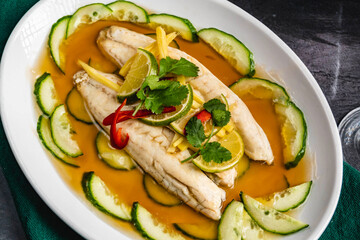A close-up of a plate with steamed sea bream, Steamed Salmon Recipe, swirling silverfish, cucumber