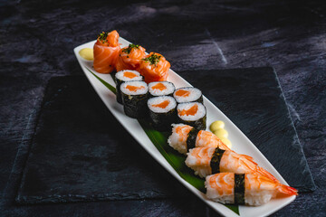 A white plate topped with sushi on top of a black table, twisted shapes, three towers, long flowing fins