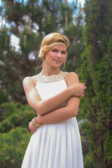 blonde beautiful natural girl with blonde hair in a white dress in nature, on the street, in the garden by a tree, with makeup and hairstyle, greek woman in a white ethnic historical dress, retro