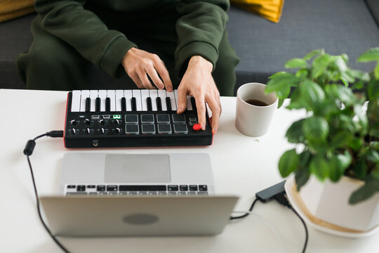 Top view of music producer or arranger using laptop and midi keyboard and other audio equipment to create music at home studio. Beat making and arranging audio content and composing song concept