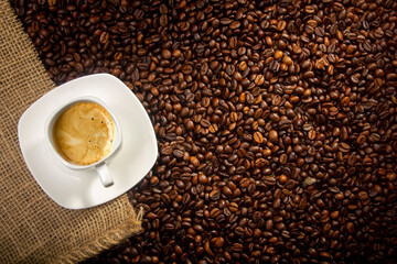 Coffee break background. Hot coffee in cup and roasted coffee beans on a wooden table. Copy space