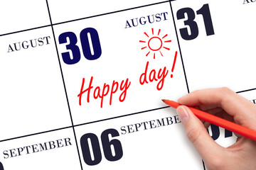 Hand writing the text HAPPY DAY and drawing the sun on the calendar date August 30