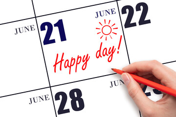 Hand writing the text HAPPY DAY and drawing the sun on the calendar date June 21