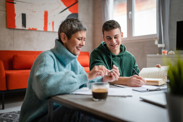 One student teenage caucasian man study learn with help of his tutor professor or mother senior woman at home having private lesson to prepare for exam education concept real people copy space