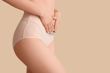 Young woman in menstrual panties on beige background, closeup