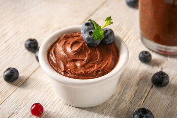 Bowl of delicious chocolate pudding, blueberry and mint on white table