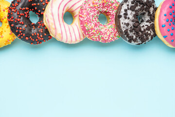 Line made of different delicious donuts on blue background