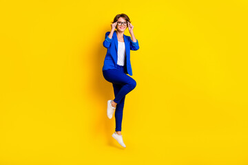 Fototapeta na wymiar Full length photo of sweet charming lady dressed blue blazer jumping high hands arms spectacles isolated yellow color background