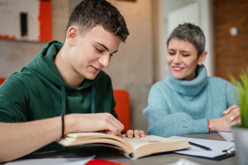 One student teenage caucasian man study learn with help of his tutor professor or mother senior woman at home having private lesson to prepare for exam education concept real people copy space - obrazy, fototapety, plakaty