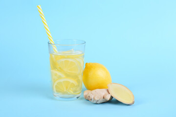 Fototapeta premium Fresh cut ginger, glass of water and lemon on blue background