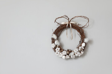 Easter wreath with quail eggs hanging on light wall