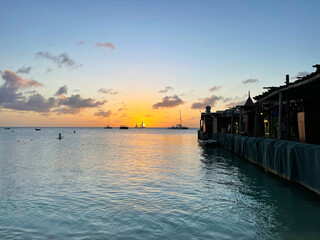 Obraz premium Sailboats on the horizon at sunset, on the Caribbean sea, off the coast of Aruba