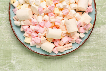 Plate with sweet marshmallows on color wooden background, closeup