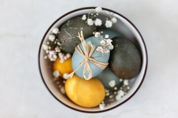 Multicolored Easter eggs in a bowl, view from above. Festive decoration.