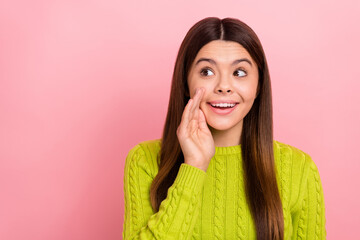 Photo portrait of cute young girl cover mouth look interested empty space dressed stylish green outfit isolated on pink color background