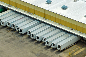 Aerial view of large commercial distribution center with many trucks unloading and uploading retail...
