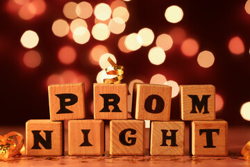 Wooden cubes with text PROM NIGHT on table against blurred lights © Pixel-Shot