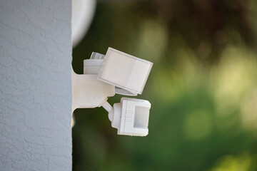 Motion sensor with light detector mounted on exterior wall of private house as part of security...