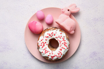 Plate with tasty Easter cake, eggs and toy bunny on light background