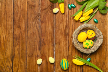 Composition with nest of Easter eggs and beautiful tulip flowers on wooden background