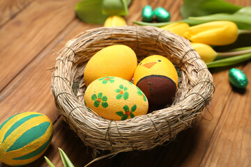 Nest with painted Easter eggs on wooden table, closeup