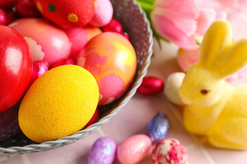 Obraz na płótnie Canvas Bowl with painted Easter eggs and bunny on table, closeup