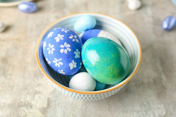 Bowl with painted Easter eggs on light background