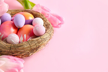 Fototapeta na wymiar Nest with beautiful Easter eggs and tulip flowers on pink background